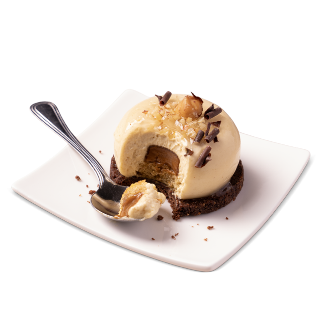 Kuppelförmiges Karamellmousse auf Schokoladenkeksboden, mit Haselnüssen und Schokoladenraspeln, angebissen