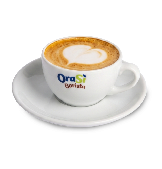Weiße Cappuccinotasse mit herzförmiger Latte-Art, Aufschrift "OraSì Barista", auf passender Untertasse, weißer Hinter...