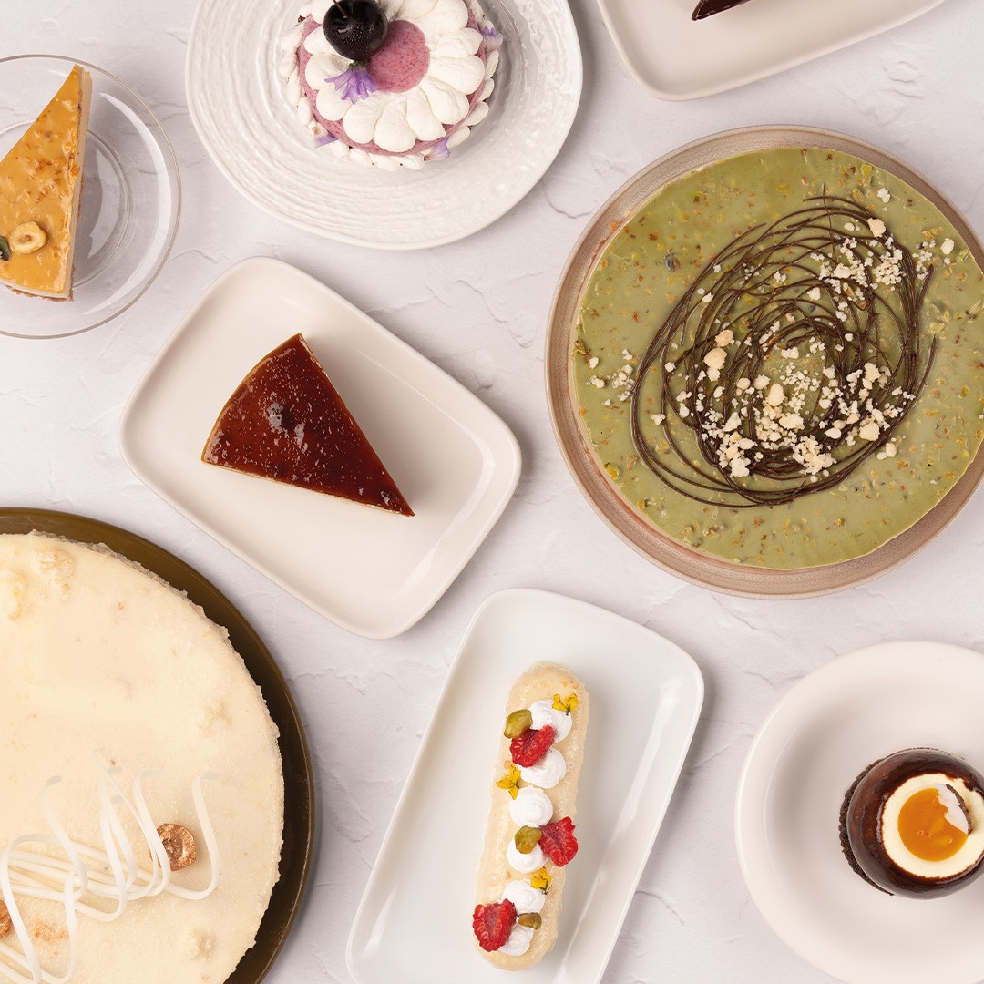 Draufsicht auf verschiedene Desserts: Cheesecake, Flan, Pistazientarte, Eclair und Schokoladenmousse-Becher