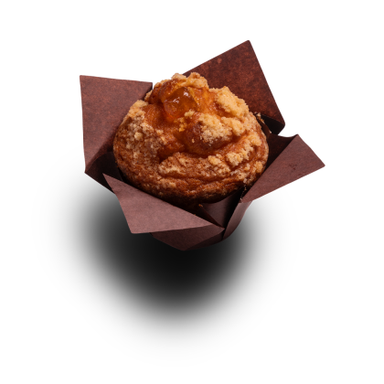 Goldener Muffin mit Streuseln und Fruchtfüllung, in brauner Papierform, auf weißem Hintergrund.