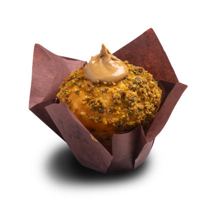 Muffin mit gehackten Pistazien überzogen, mit Karamell-Frosting-Wirbel, in brauner Tulpenform.