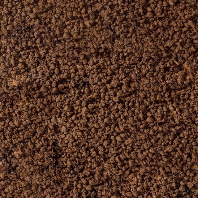 Nahaufnahme von krümeliger brauner Erde oder Kaffeesatz mit grober, körniger Textur.