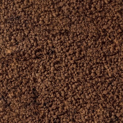 Nahaufnahme von krümeliger brauner Erde oder Kaffeesatz mit grober, körniger Textur.