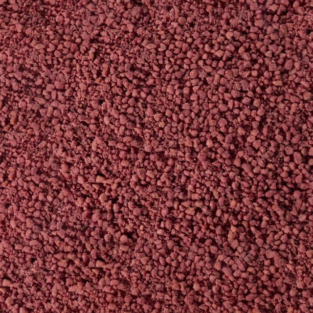 Nahaufnahme grober, rotbrauner Granulate oder Pulver, ähnlich verklumpten Mineral- oder Gewürzkörnern
