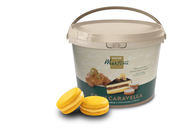 Beiger Eimer Streichcreme Master Martini Gran Caravella neben zwei gelben Macarons und einem gefüllten Gebäck.