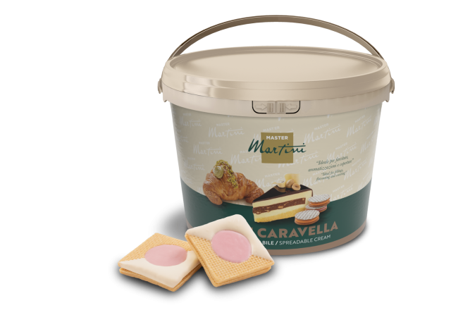 Beigefarbener Eimer Master Martini Caravella Streichcreme neben zwei quadratischen Keksen mit rosa Füllung.