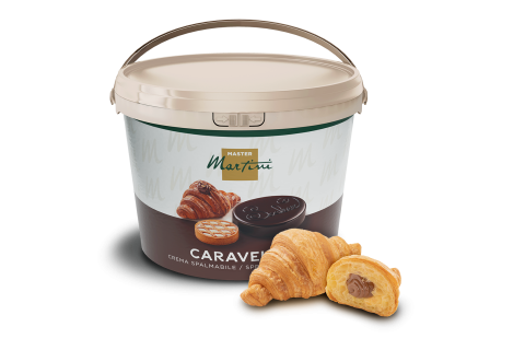Beigefarbener Eimer Caravel Master Martini Schokoladencreme neben zwei Croissants, eines mit Schokolade gefüllt.