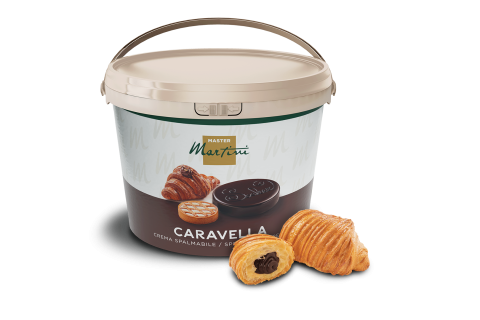 Großer Eimer Schokoladen-Brotaufstrich Master Martini Caravella neben zwei Croissants mit Schokoladenfüllung.