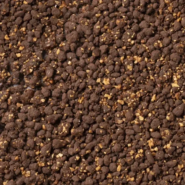 Nahaufnahme einer krümeligen, dunkelbraunen Masse mit gehackten Nüssen, ähnlich einem Schokoladen-Crumble.