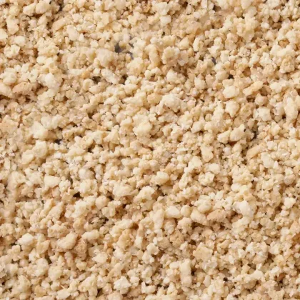 Nahaufnahme heller, krümeliger Granulate mit grober, bröseliger Textur über das gesamte Bild.